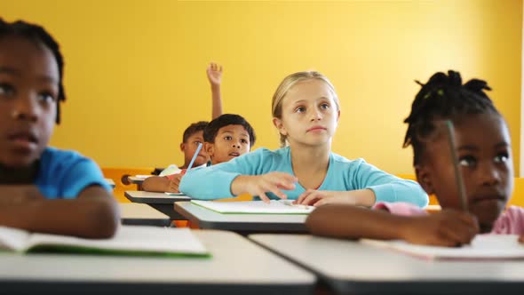 School kids raising hand in classroom