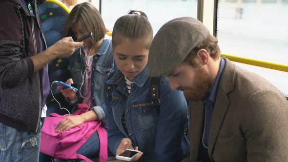 Young Woman and Man Talking about Gadgets in Trolleybus