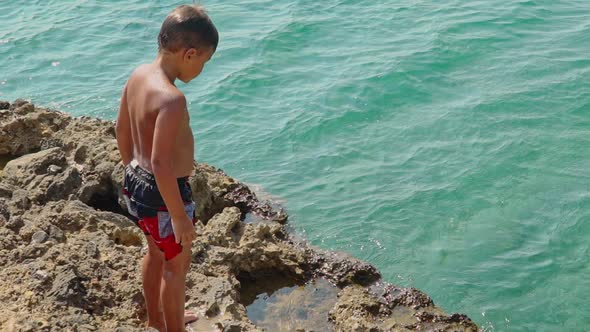 Caucasian boy prepares to jump from rocks to the sea, Kalamata , Greece , slow motion