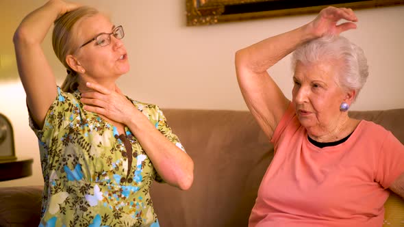 Front view closeup of home healthcare nurse helping elderly woman with arm stretches.