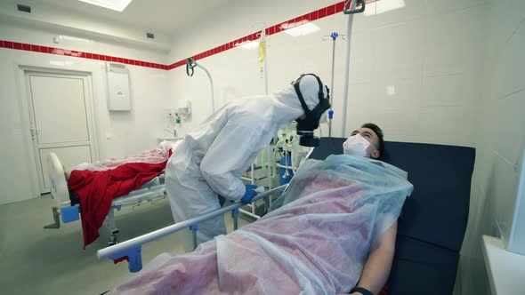 Doctor in a Hazmat Suit Is Checking Temperature of a Lying Patient, Covid-19, Pandemic, Virus