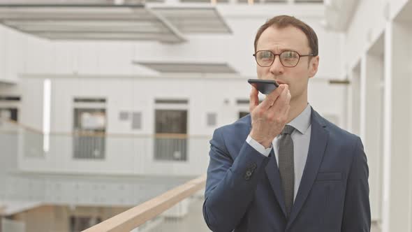 Portrait of Businessman Recording Voice Message on Smartphone