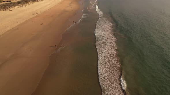 Aerial View of Waves Crashing on Calm Beach