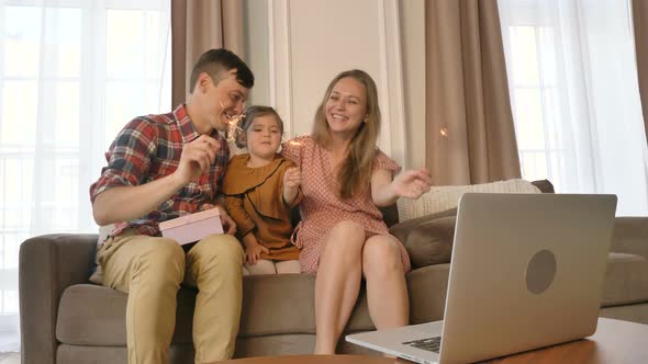 Happy Family with Sparklers Communicates Online with Their Relatives, Congratulates on the Holiday