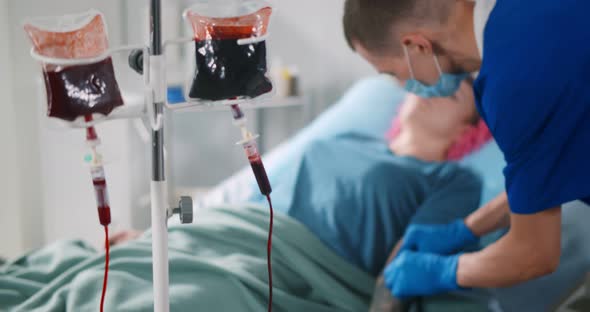 Nurse Injecting Syringe in Female Patient Arm for Blood Transfusion