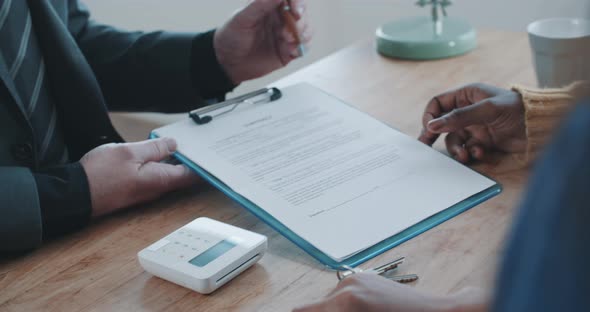 Mature businessman discussing document with two clients in the office