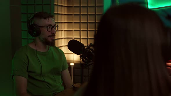 Young man talking in mic while recording podcast with crop coworker