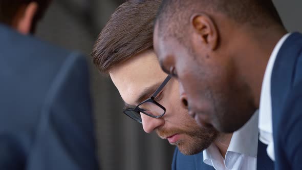 Discussion of work issues at a meeting in the office: young businessmen working as a team