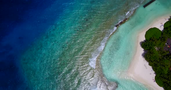 Daytime above tourism shot of a white paradise beach and aqua blue water background in vibrant 4K