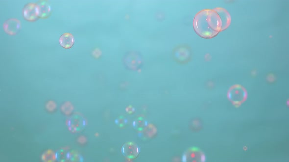 Beautiful Colorful Soap Bubbles Illuminated By Pink Light Fly Indoors on a Blue Background