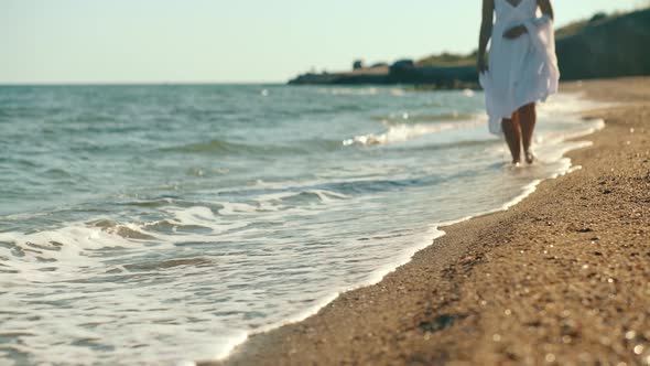 Slim Female Legs and Feet Walking Along Sea Water Waves on Sandy Beach