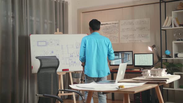 Asian Man Engineer With A Laptop Drawing Blueprint On The Whiteboard At The Office