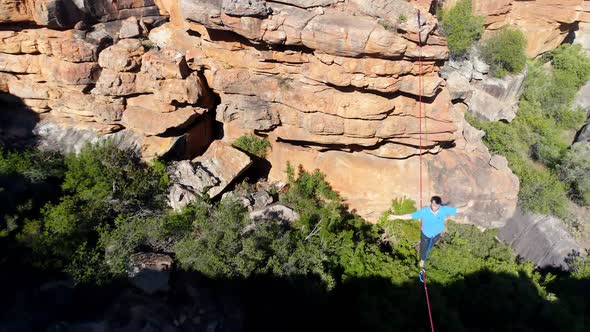 Male highliner walkng on a rope over rocky mountains 4k