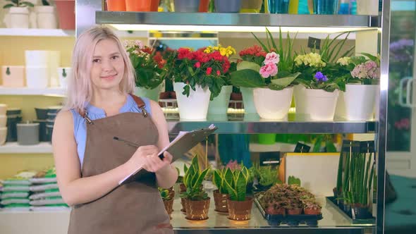 Nice Lady Holds Black Folder Smiling Against Home Plants