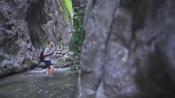 Young man standing by stream in amazing nature.