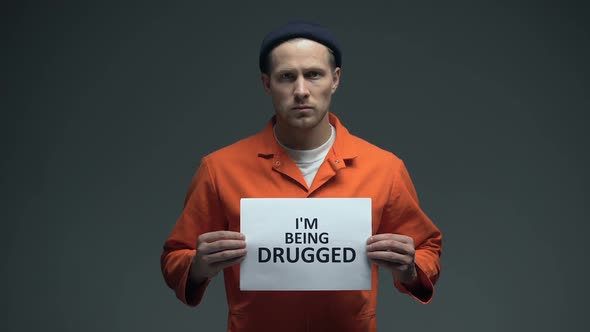 European Imprisoned Man Holding I Am Being Drugged Sign in Cell, Warning, Addict
