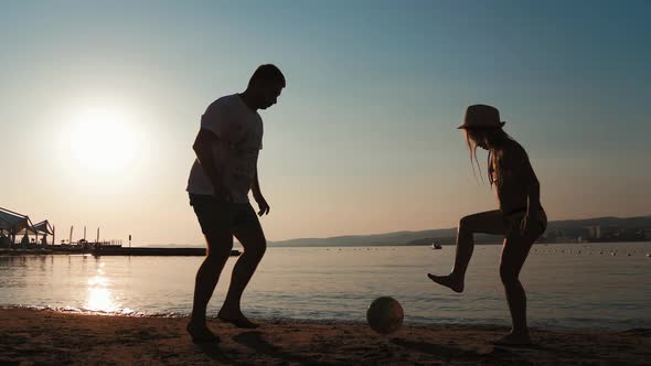Family Playing Football on a Beach in Summer Day. Father and Daughter Playing Soccer Outdoors