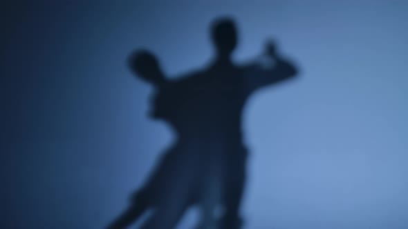 Dancing Shadows of Ballroom Dancers Performing Argentine Tango on a Blue Studio Background