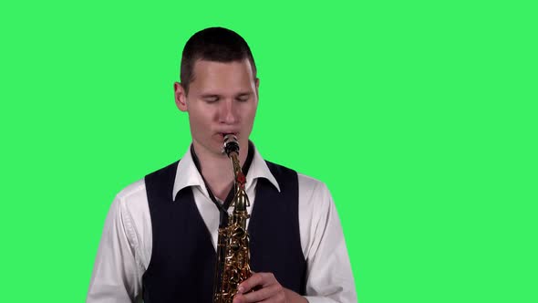 Portrait Stylish Young Guy Plays Slow Melody at Saxophone on a Green Screen in the Studio