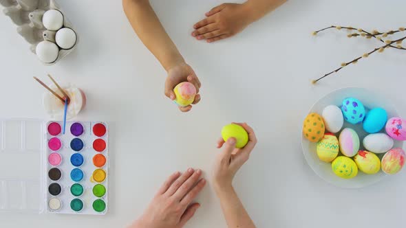 Hands of Child and Parent Beating Easter Eggs