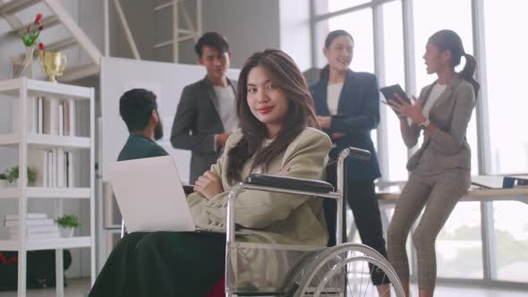 A disabled company employee is able to work happily with colleagues in the office.