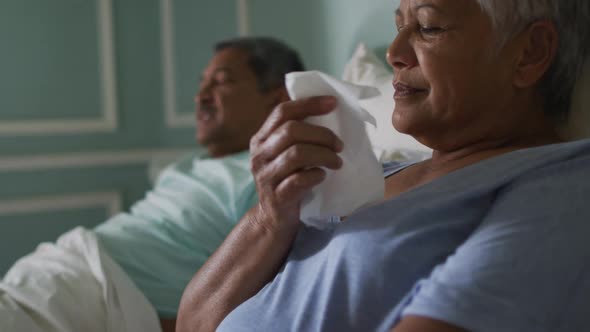 Senior mixed race couple both ill in bed