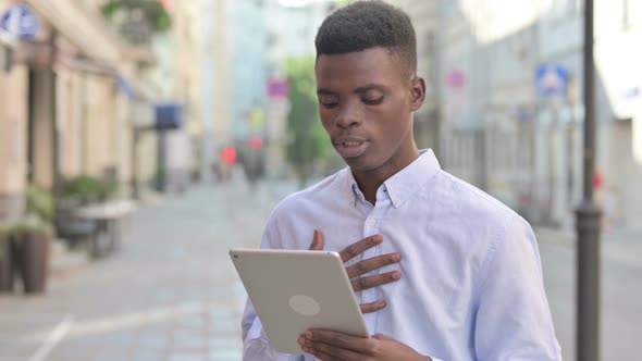 African Man Talking on Video Call on Tablet in Street