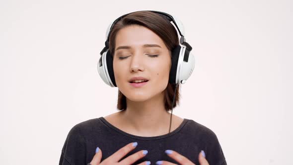 Portrait of Young Pretty Girl Listening Music in Headphones Singing and Dancing