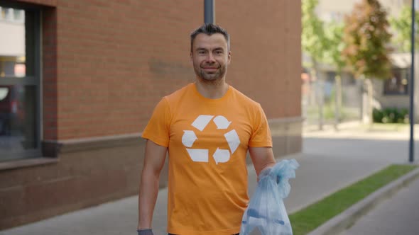 Male Volunteer is Standing and Holding a Ball with Sorted Garbage Wearing Special Uniform and Gloves