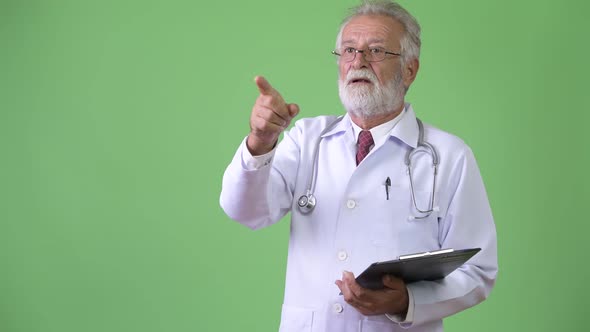 Handsome Senior Bearded Man Doctor Against Green Background