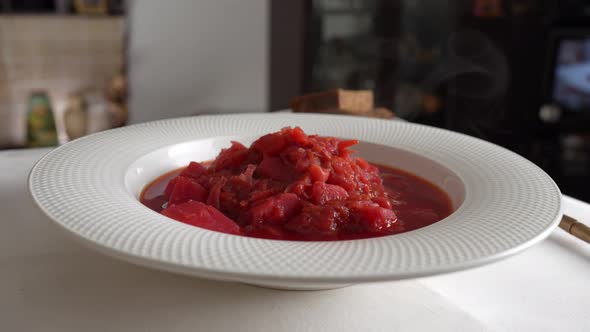 Plate of red beetroot soup borsch rotates on table. Traditional Ukraine food