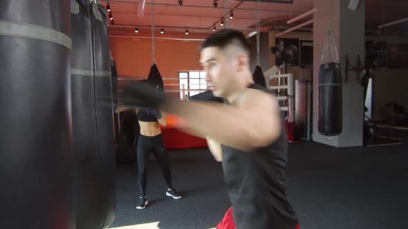 Male and Female Boxers Hitting Heavy Bags in Gym