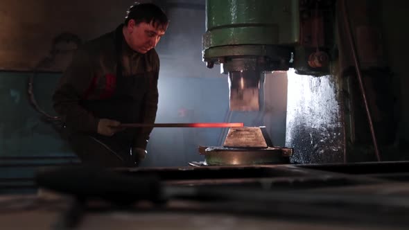 Man Blacksmith Thinning an Oblong Piece of Metal Under an Automatic Press