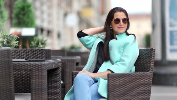 Smiling Glamour Female Relaxing Sitting on Chair at Outdoor Cafe Enjoying Break at City Background