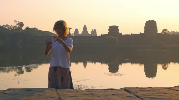 Slow motion: woman taking selfie at Angkor Wat ruins at sunrise