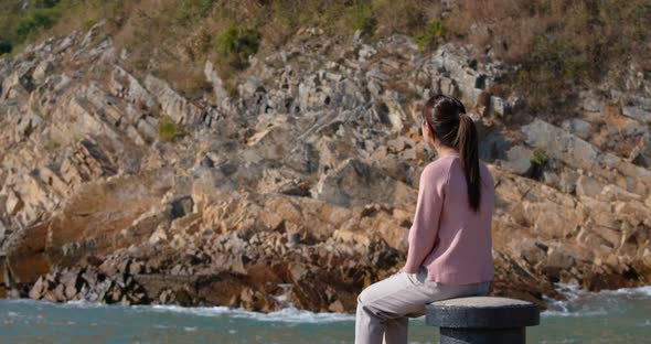 Woman look at the sea and sit on the pier