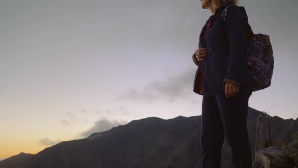 Mature Woman on a High Mountain Landscape Watching the Sun Set Over the Horizon