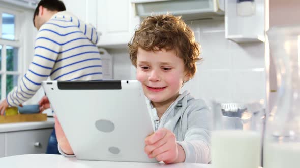 Father talking on mobile phone while son using digital tablet