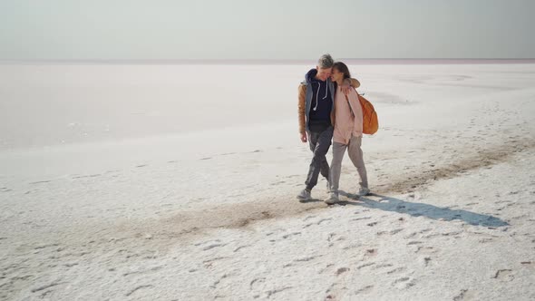 Happy Smiling Lovely Couple Travelers Walking Hugging Each Other on Deserted Pink White Salty Coast