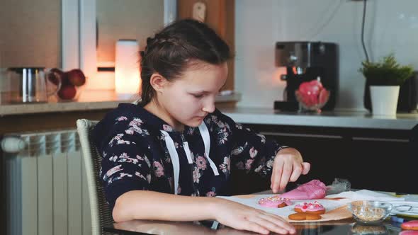 Cheerful Young Girl Helping Her Mother To Decorate Cookies for the Holiday Celebration