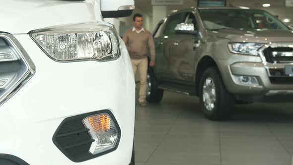 A Solid Man Walks Among Cars at the Car Dealership