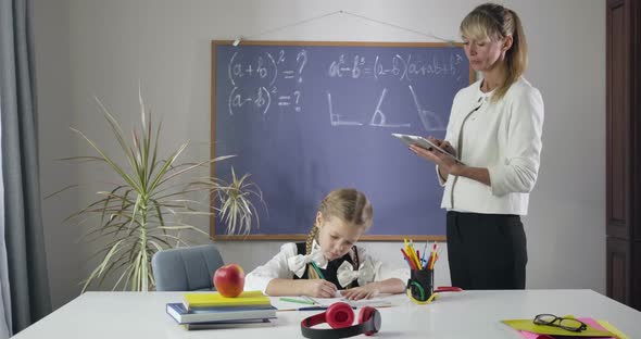 Pretty Caucasian Girl Drawing in Exercise Book As Adult Private Teacher Searching Tasks in Tablet