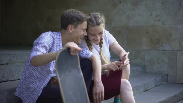 Laughing Skaters Watching Tutorial Video on Cell Phone, Mobile Application