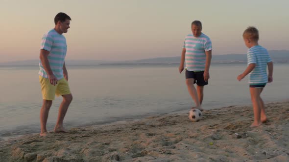 Men of Three Generations Playing Football on Beach