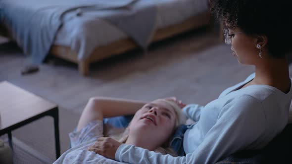 Young Girl Laying on a Lap of Her Girlfriend on the Couch Playing with Hands