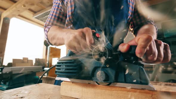 A Carpenter Whittles Wooden Stick with an Instrument