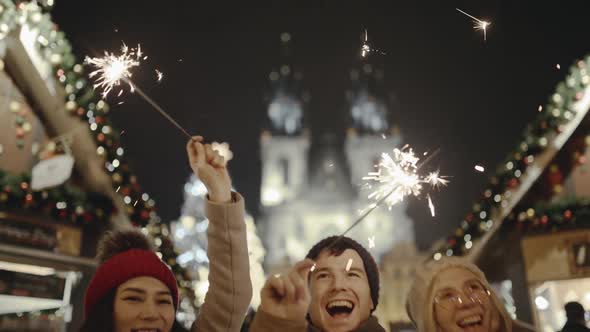 Pretty Young Friends Laughing and Dancing with Sparklers in the Street