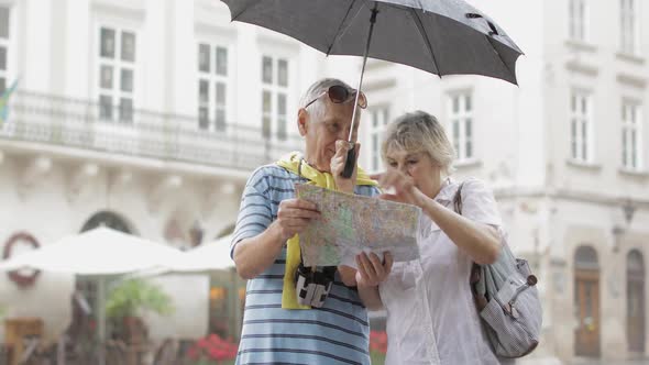 Happy Senior Tourists Stand Downtown and Enjoy the Rainy Weather in Lviv