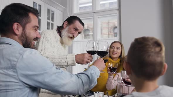 Smiling Senior Grandfather Clinking Glass with All Members of Family During Celebration