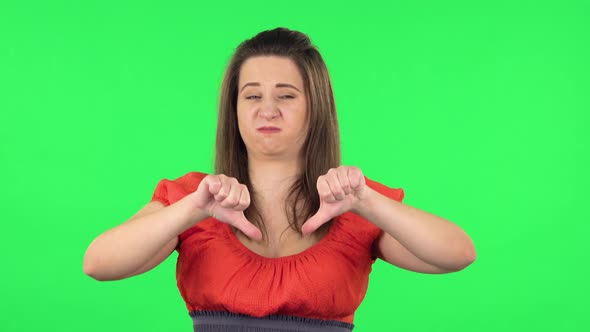 Portrait of Cute Girl Showing Thumbs Down Gesture. Green Screen